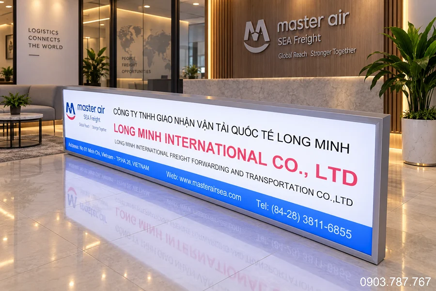 Bảng tên công ty dạng hộp đèn chân đứng, thiết kế nền trắng phối xanh – đỏ, nội dung chữ rõ ràng và nổi bật, tạo cảm giác chuyên nghiệp, hiện đại cho khu vực lễ tân.